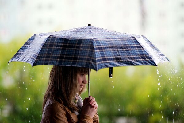 Morena chica con paraguas bajo la lluvia