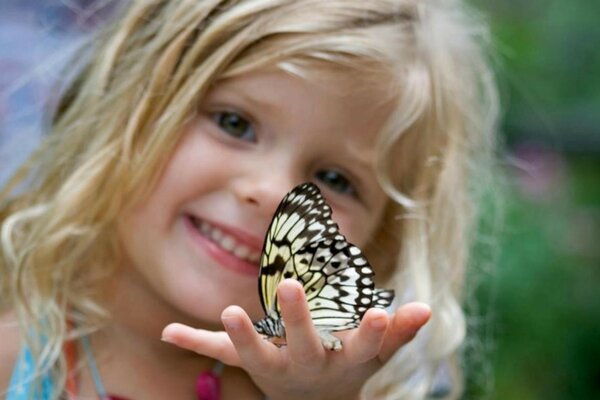 Chica rubia con una mariposa en la mano