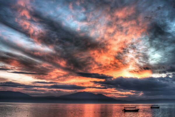 Barcos en la superficie del mar bajo el cielo al atardecer