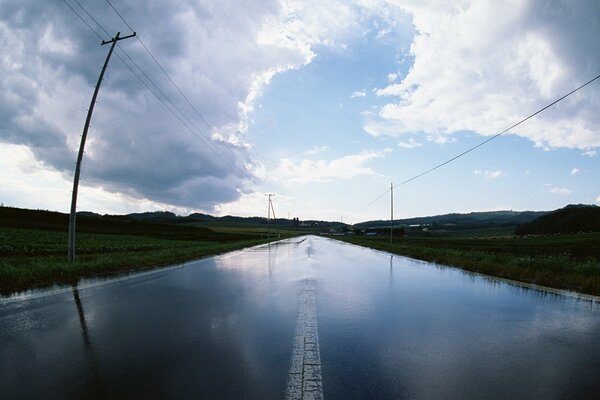 Un camino que se extiende hacia el horizonte, con pilares a lo largo de las carreteras y un cielo con grandes nubes