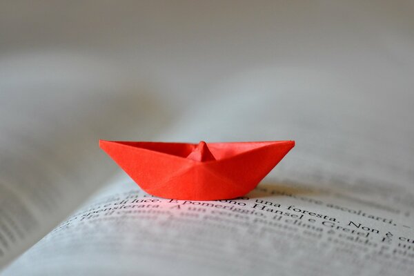 Un barco rojo de papel en la página de un libro