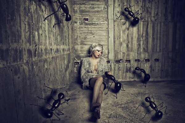 Chica sentada en la arena en un granero con enormes hormigas