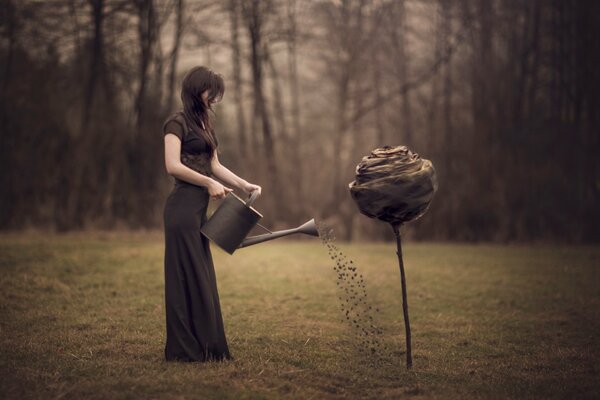 Chica regando una enorme flor