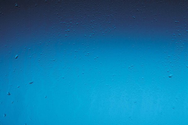 Gotas de lluvia sobre el fondo azul de la ventana