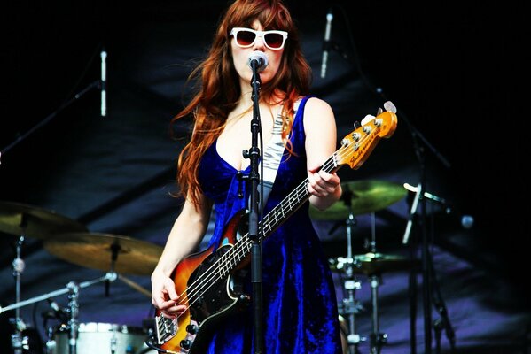 La cantante Jenny Lewis, de pie en el escenario y tocando la guitarra