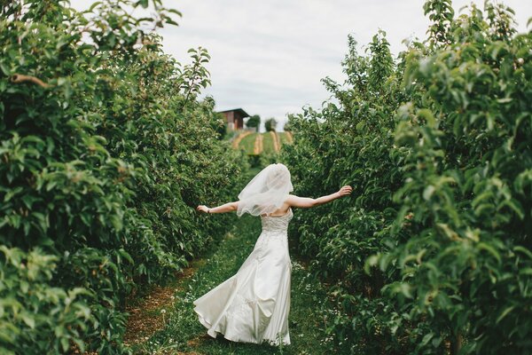 Una novia con un vestido blanco corre por el camino
