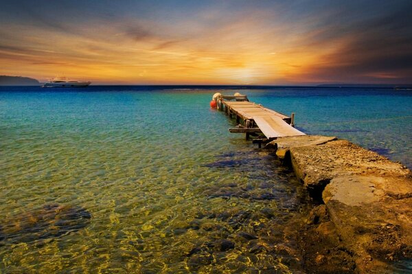 Puente que sale al mar en medio de la puesta de sol